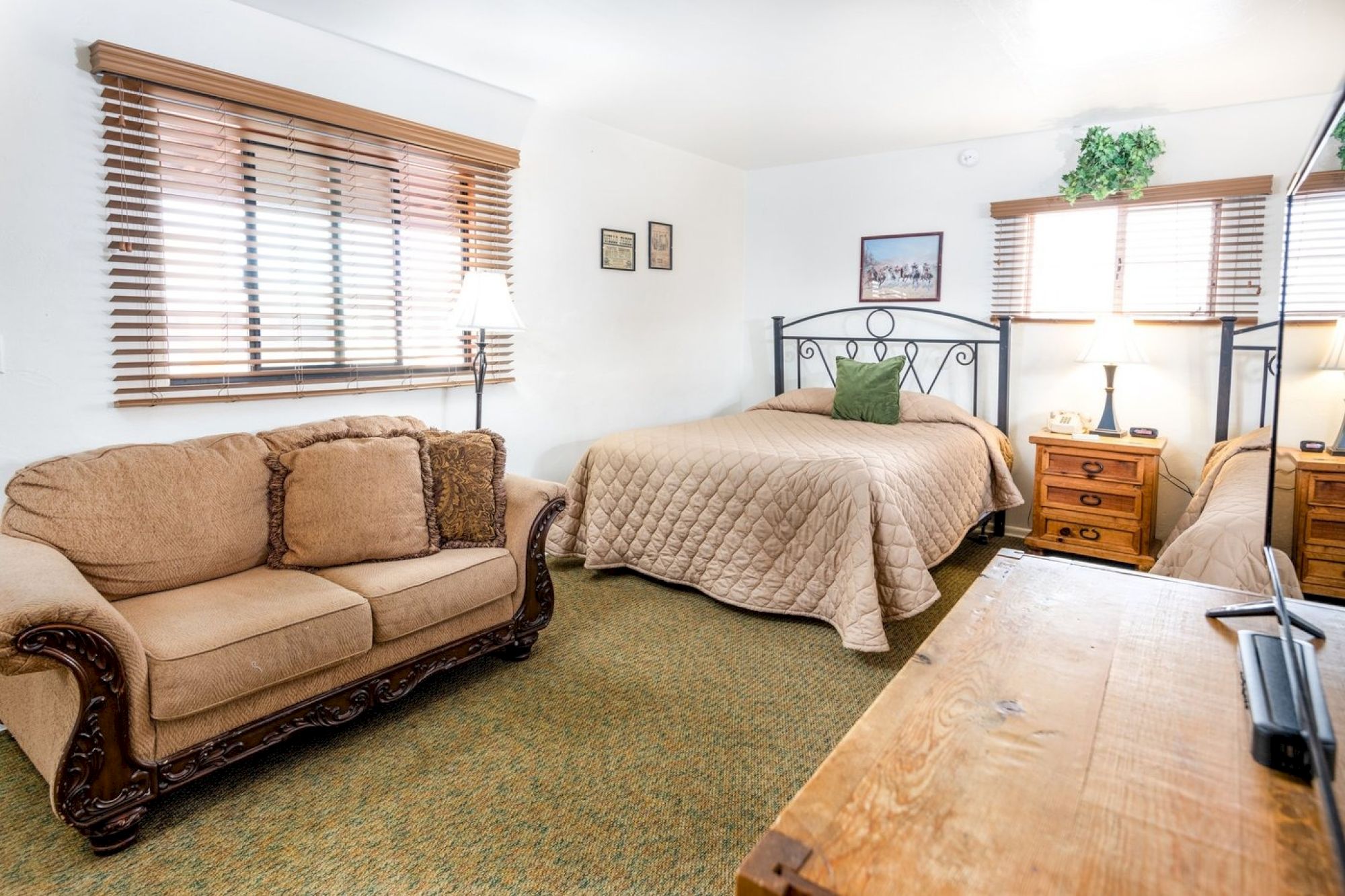 A cozy room with a bed, sofa, wooden furniture, lamps, and decorative elements, creating a warm and inviting atmosphere.