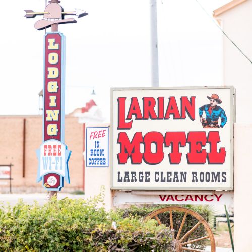A vintage motel sign reads "Larian Motel" with "Large Clean Rooms" and "Vacancy" indicated, along with &ldquo;Free WiFi&rdquo; offered.